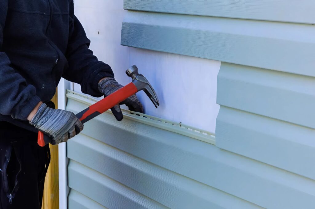 Siding panel repair and surface prep by a painter in Andover, KS, before exterior painting